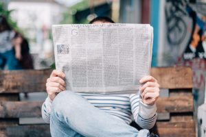 Wat is free publicity? PR Goeroes legt het uit. Op de afbeelding zie je iemand die op een houten bankje de krant leest. 