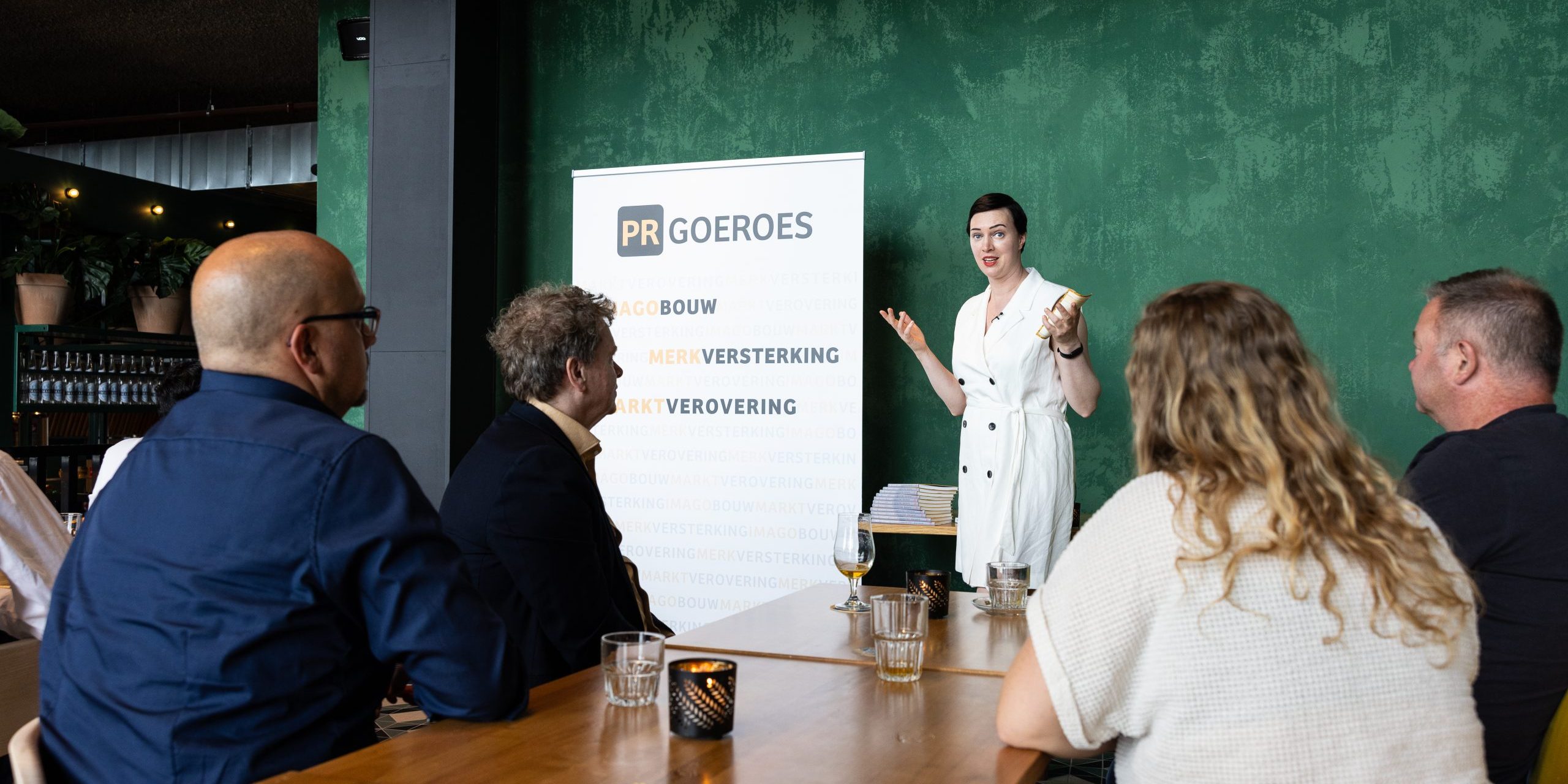 Wie is het beste PR-bureau van Nederland? Jennifer Delano, founder van PR-goeroes, geeft een presentatie aan een groep in een vergaderruimte en licht de strategische aanpak van het bureau toe.